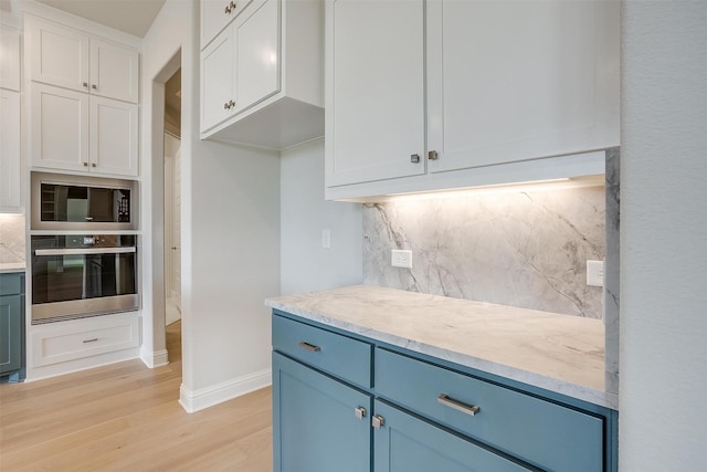 kitchen with light hardwood / wood-style floors, tasteful backsplash, oven, and white cabinets