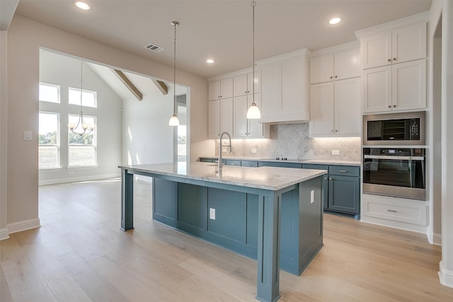 kitchen with black appliances, lofted ceiling with beams, light hardwood / wood-style floors, white cabinets, and a center island with sink