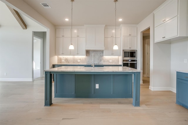 kitchen with an island with sink, hanging light fixtures, white cabinetry, light hardwood / wood-style floors, and stainless steel appliances