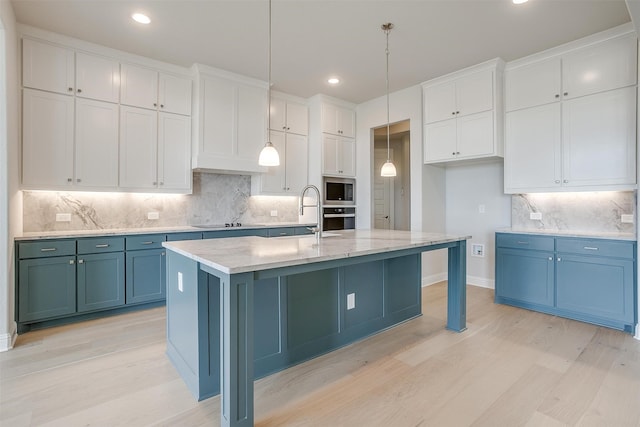 kitchen with decorative backsplash, an island with sink, stainless steel appliances, decorative light fixtures, and white cabinets