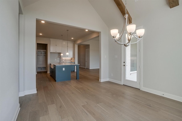 interior space featuring an island with sink, a kitchen breakfast bar, white cabinetry, light hardwood / wood-style flooring, and pendant lighting