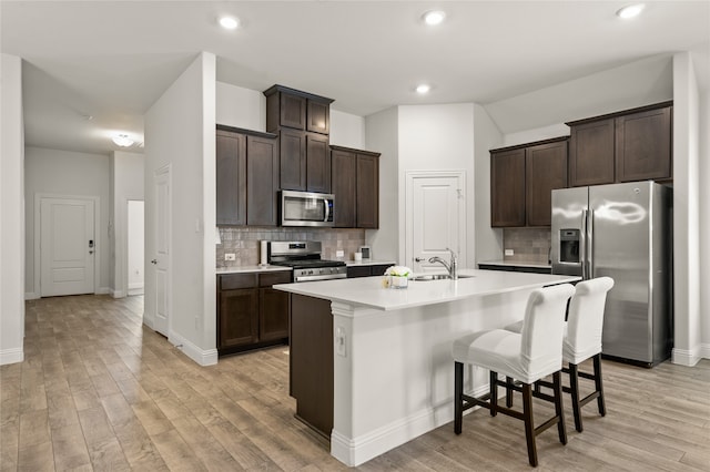 kitchen featuring light hardwood / wood-style floors, stainless steel appliances, a center island with sink, tasteful backsplash, and sink