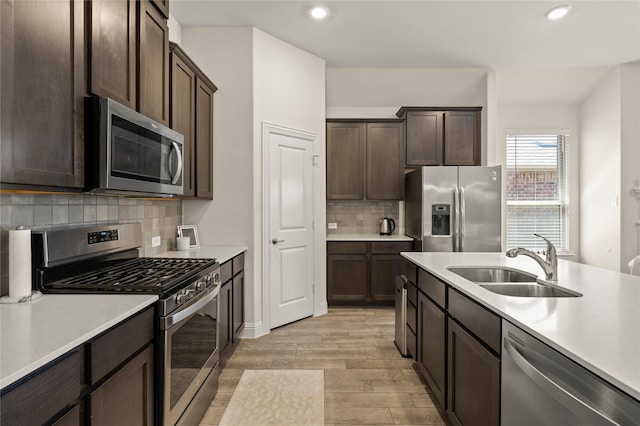 11024 Los Alamos Dr, Aubrey, TX 76227 - kitchen featuring stainless steel appliances, a sink, light wood-type flooring, dark brown cabinets, and light countertops
