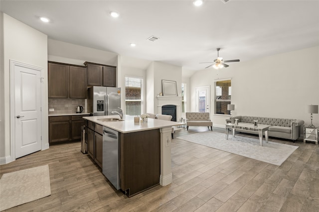 kitchen with backsplash, ceiling fan, an island with sink, appliances with stainless steel finishes, and sink