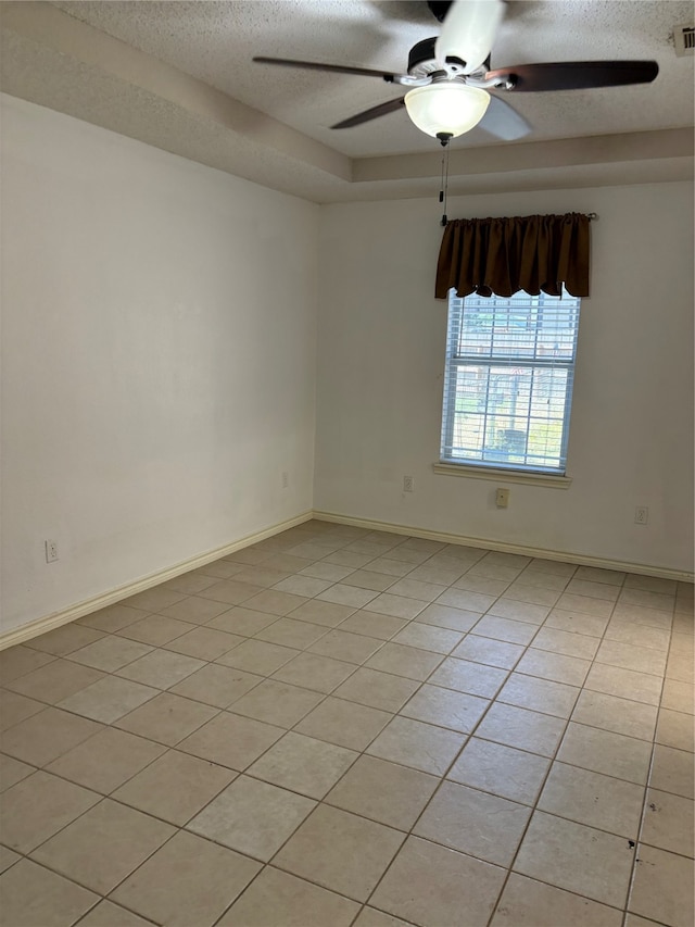 spare room featuring ceiling fan, a textured ceiling, and light tile floors