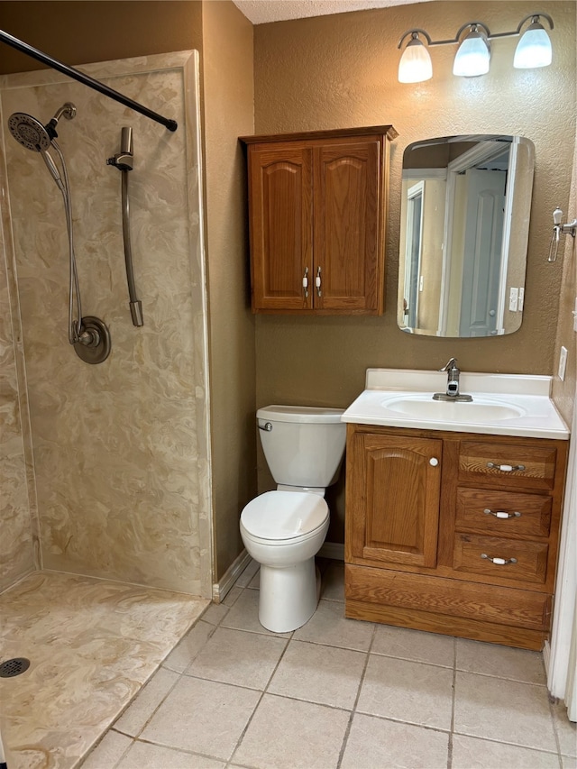 bathroom with a tile shower, vanity, toilet, and tile floors