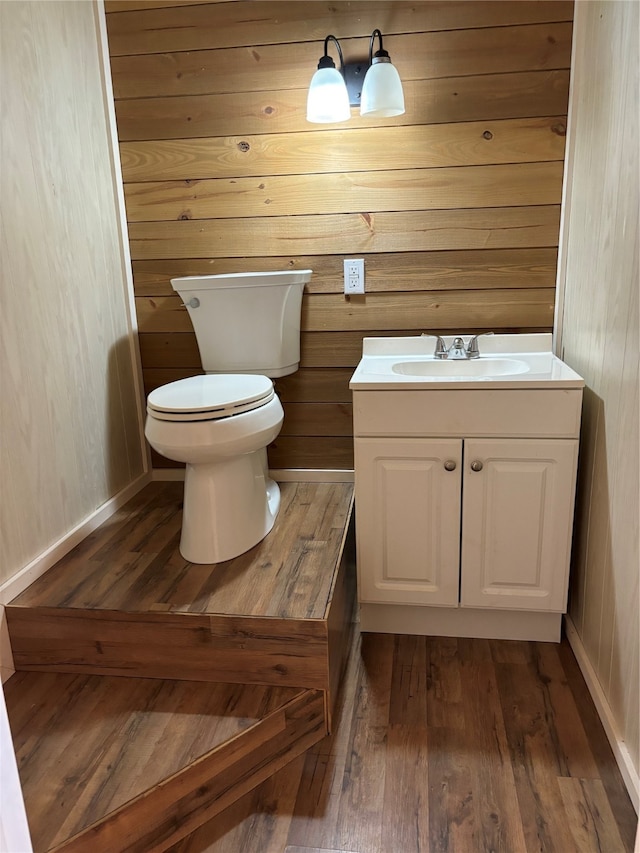 bathroom featuring wooden walls, vanity, toilet, and hardwood / wood-style flooring