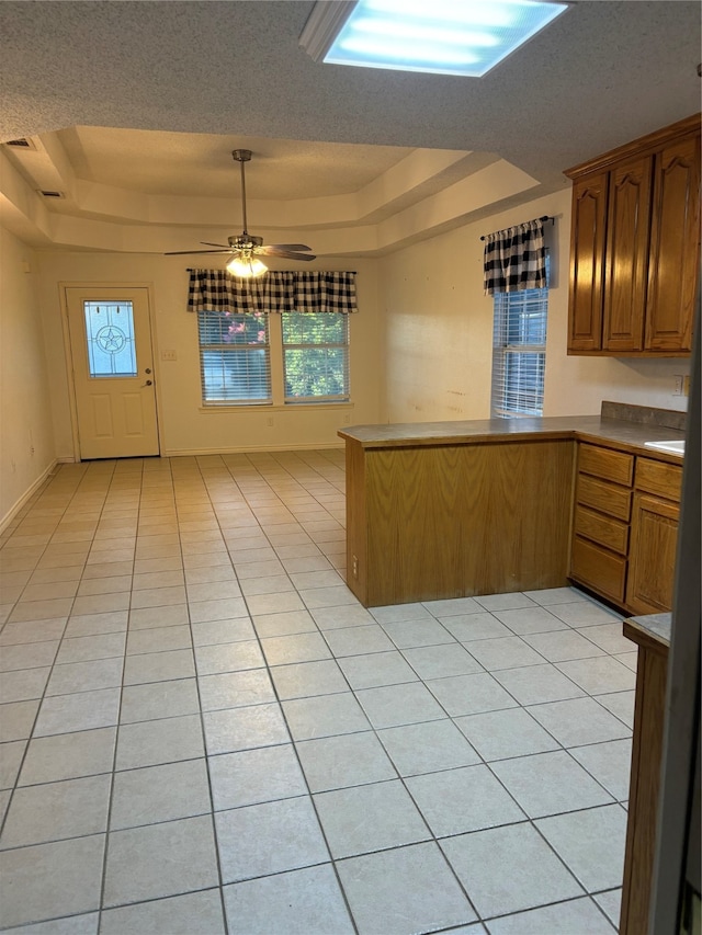 kitchen featuring a tray ceiling, ceiling fan, and light tile floors