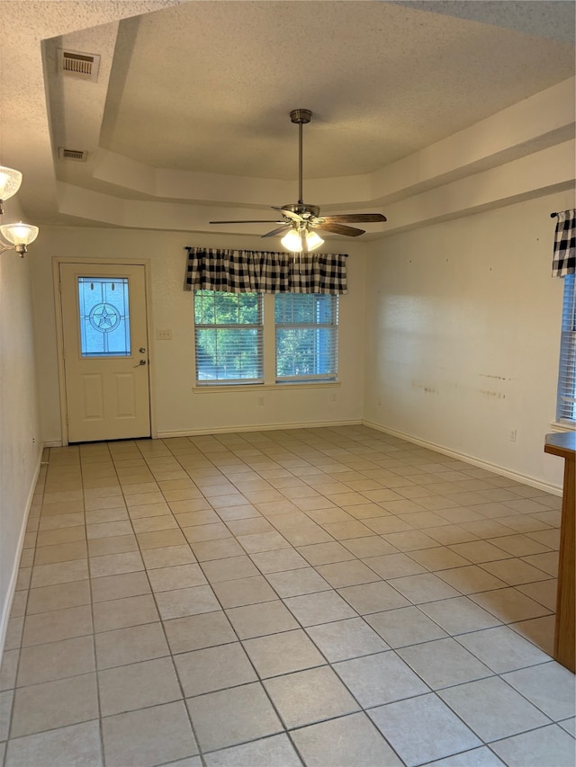 tiled spare room with ceiling fan, a raised ceiling, and a textured ceiling