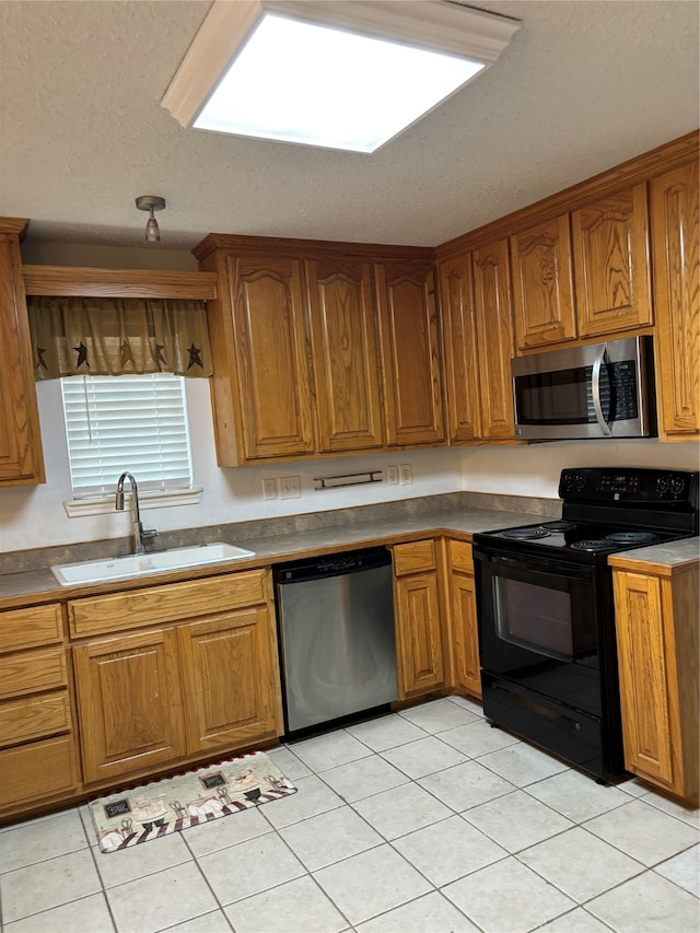 kitchen featuring stainless steel appliances, sink, and light tile floors