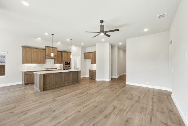 kitchen featuring light wood-type flooring, an island with sink, and hanging light fixtures