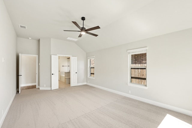 unfurnished bedroom with vaulted ceiling, ceiling fan, multiple windows, and ensuite bath