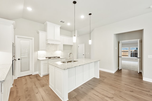 kitchen featuring a kitchen island with sink, light hardwood / wood-style flooring, sink, white cabinetry, and light stone counters