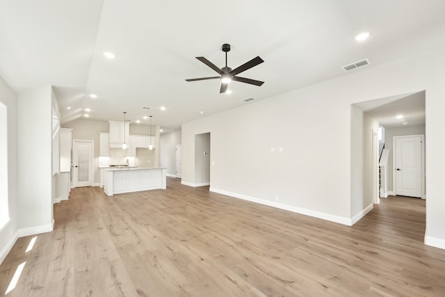 unfurnished living room featuring ceiling fan, vaulted ceiling, and light wood-type flooring