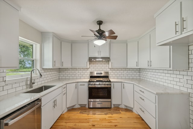 kitchen featuring stainless steel appliances, sink, white cabinetry, ceiling fan, and light hardwood / wood-style floors