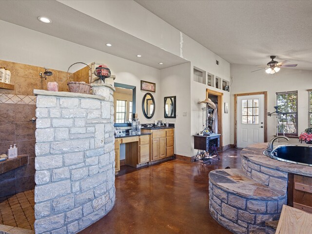 kitchen featuring a textured ceiling, tile walls, sink, and ceiling fan