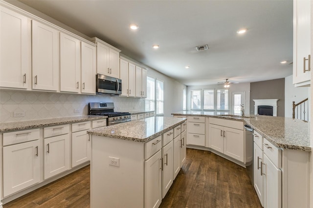 kitchen featuring ceiling fan, stainless steel appliances, white cabinets, and a center island