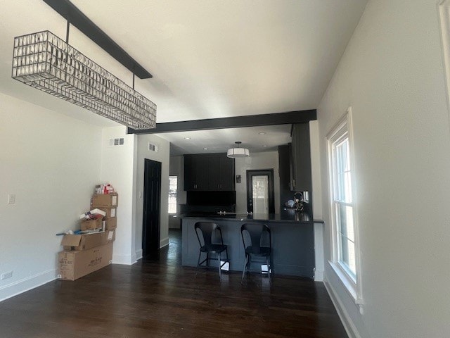 kitchen with a notable chandelier, kitchen peninsula, dark wood-type flooring, and a breakfast bar