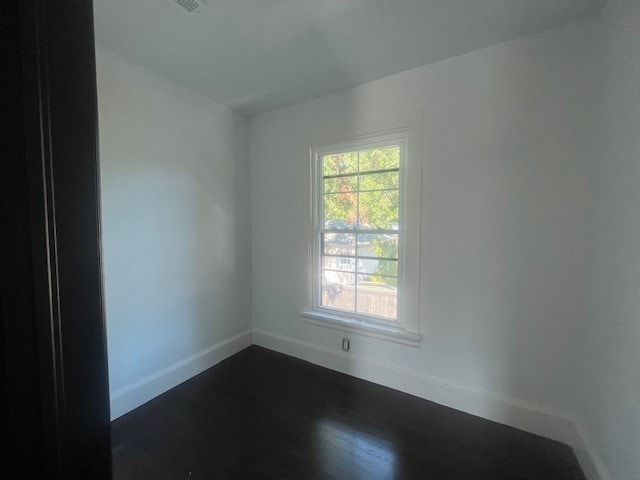 unfurnished room with dark wood-type flooring