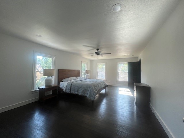 bedroom with multiple windows, ceiling fan, and dark wood-type flooring