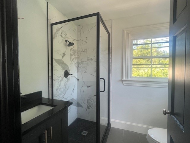 bathroom with tile patterned flooring, vanity, toilet, and an enclosed shower