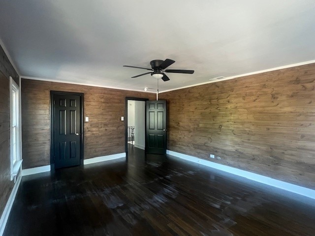 interior space with dark hardwood / wood-style flooring, ceiling fan, and wood walls