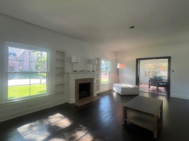 living room with built in shelves and dark wood-type flooring