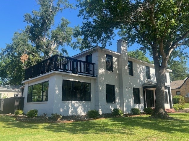 back of property with a lawn and a balcony