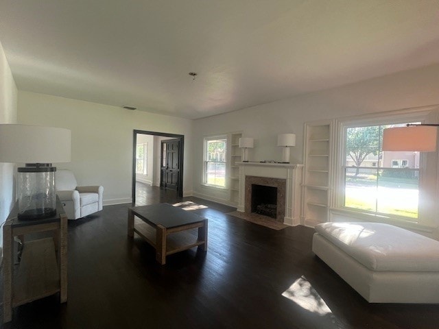 living room featuring built in features, a healthy amount of sunlight, and dark hardwood / wood-style floors