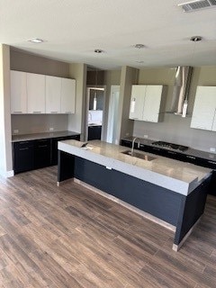 kitchen with sink, a kitchen island with sink, white cabinetry, and wood-type flooring