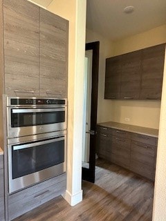 kitchen with double oven and dark wood-type flooring