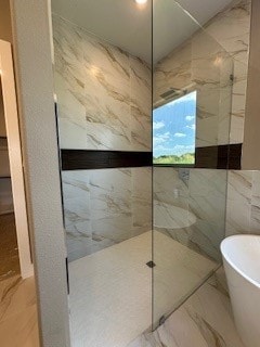 bathroom with tile flooring, a washtub, and tile walls