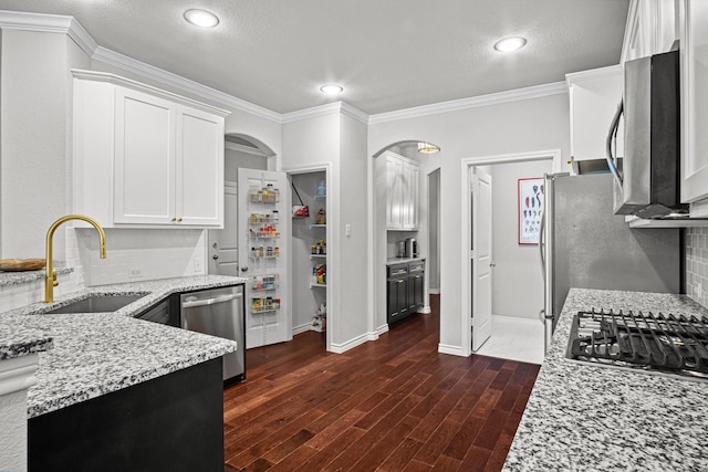 kitchen with stainless steel appliances, light stone countertops, sink, white cabinetry, and backsplash