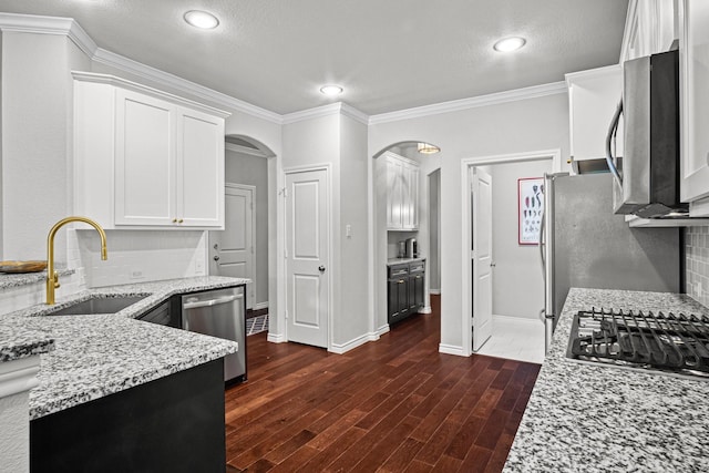 kitchen featuring sink, white cabinets, light stone counters, tasteful backsplash, and appliances with stainless steel finishes