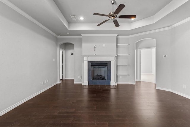 unfurnished living room with a raised ceiling, crown molding, dark hardwood / wood-style flooring, a fireplace, and ceiling fan