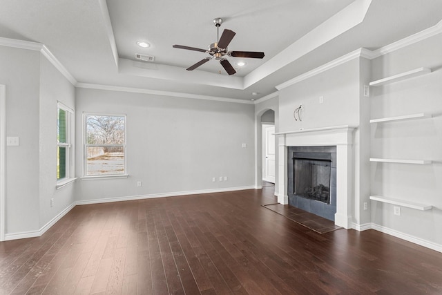 unfurnished living room featuring a tile fireplace, ceiling fan, a tray ceiling, and dark hardwood / wood-style floors