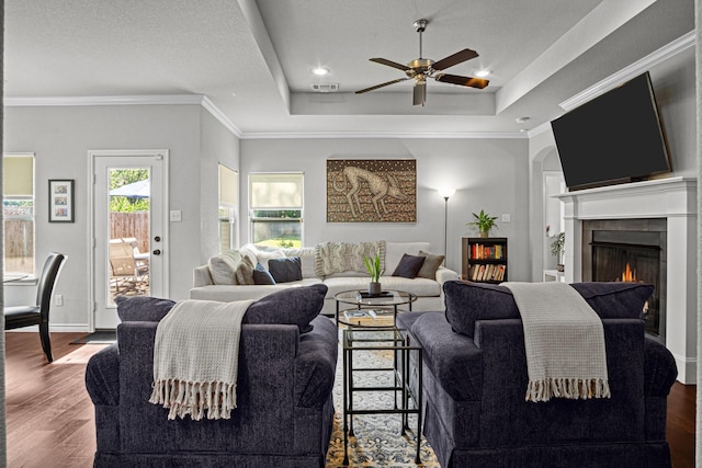 living room featuring hardwood / wood-style flooring, a raised ceiling, ceiling fan, and ornamental molding