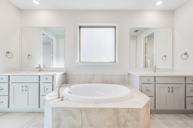 bathroom with tile patterned flooring, vanity, and tiled tub