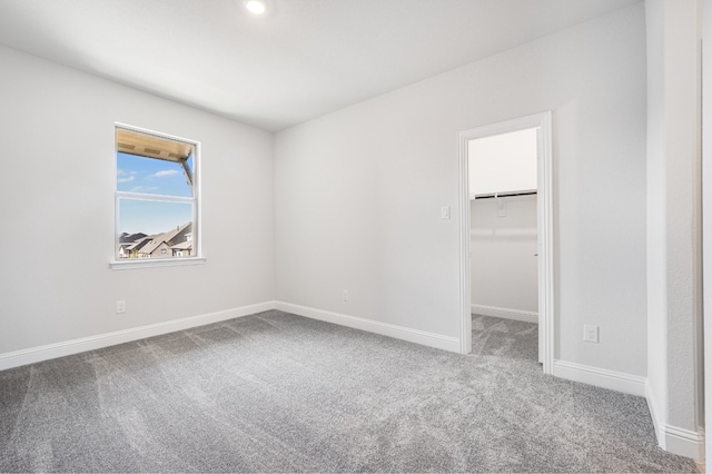 unfurnished bedroom featuring carpet flooring, a walk in closet, and a closet