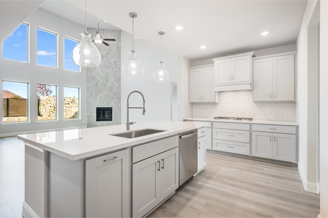 kitchen featuring sink, an island with sink, light wood-type flooring, and appliances with stainless steel finishes