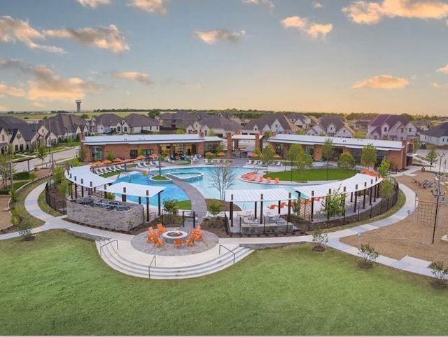 pool at dusk with a yard and an outdoor fire pit