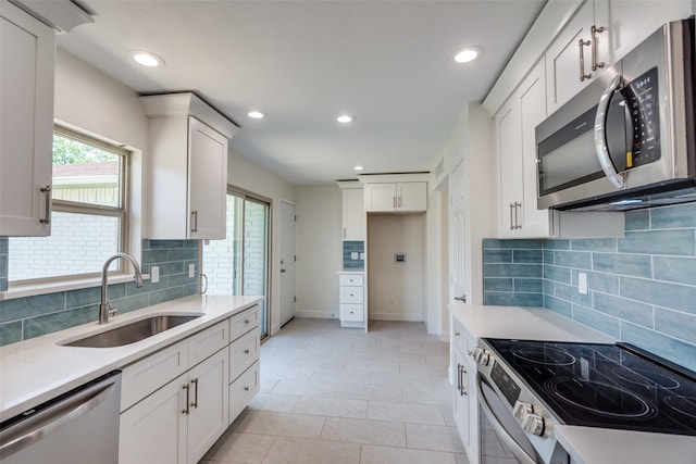 kitchen with stainless steel appliances, white cabinetry, sink, and a wealth of natural light