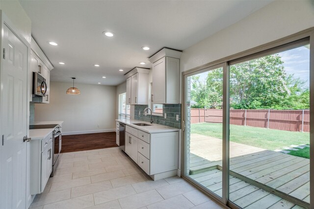 kitchen featuring sink, white cabinetry, tasteful backsplash, pendant lighting, and appliances with stainless steel finishes