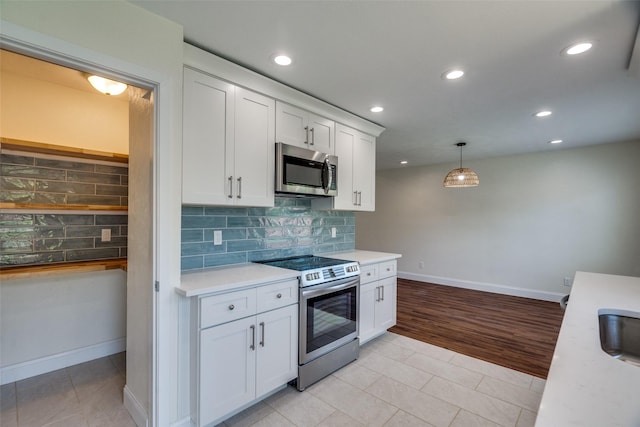 kitchen with stainless steel appliances, white cabinetry, pendant lighting, and light tile patterned floors