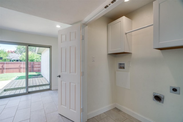 clothes washing area featuring electric dryer hookup, washer hookup, light tile patterned floors, and cabinets