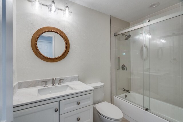 full bathroom featuring shower / bath combination with glass door, vanity, and toilet