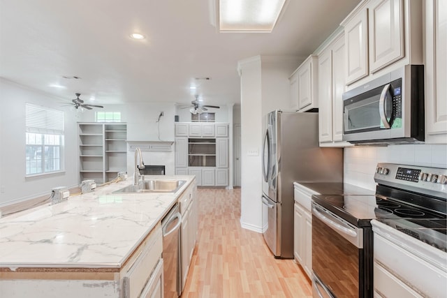 kitchen with white cabinets, an island with sink, ceiling fan, stainless steel appliances, and a sink