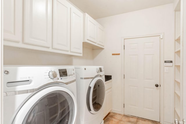 washroom with light tile patterned flooring, independent washer and dryer, and cabinet space