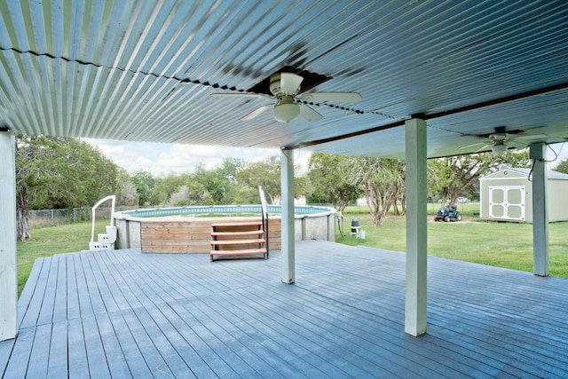 deck with an outdoor pool, an outbuilding, fence, a storage unit, and a yard