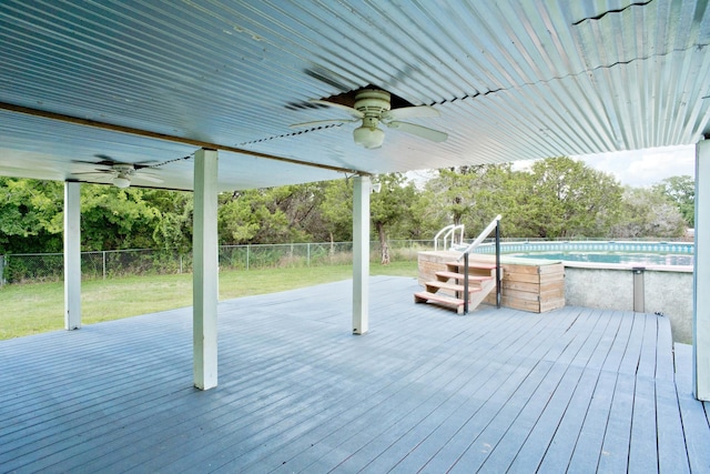 deck with a ceiling fan, a fenced backyard, an outdoor pool, and a lawn